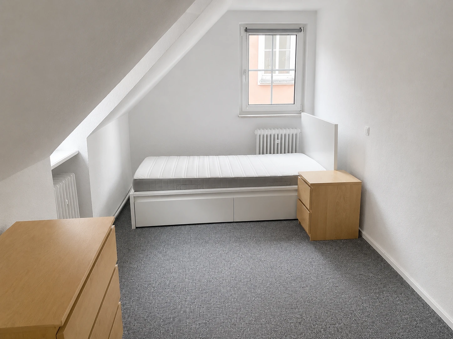 Studentenzimmer mit Dachschräge, Bett und Kommode